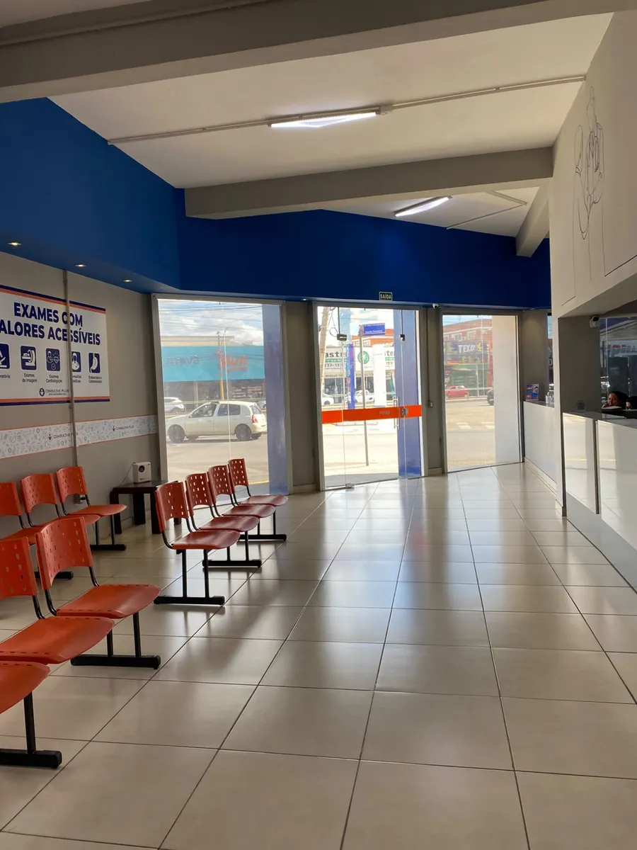 Recepção com cadeiras de espera e a fachada de vidro voltada para a rua