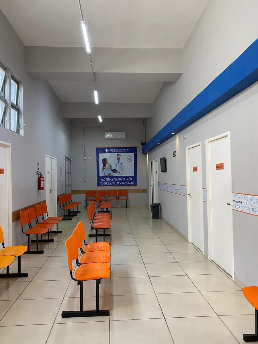 Fileiras de cadeiras na sala de espera, perto das portas dos consultórios