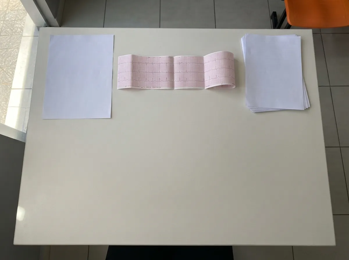 Folhas, tira de eletrocardiograma e um maço de papéis sobre a mesa